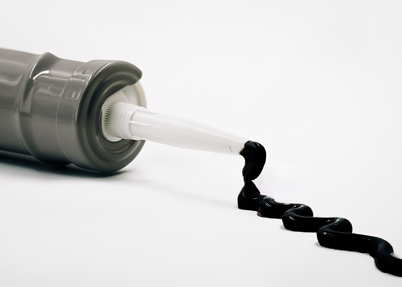 Крупний план чорного герметика, що виходить з носика картриджа для герметизації швів Крупний план чорного герметика, що виходить з носика картриджа для герметизації швів