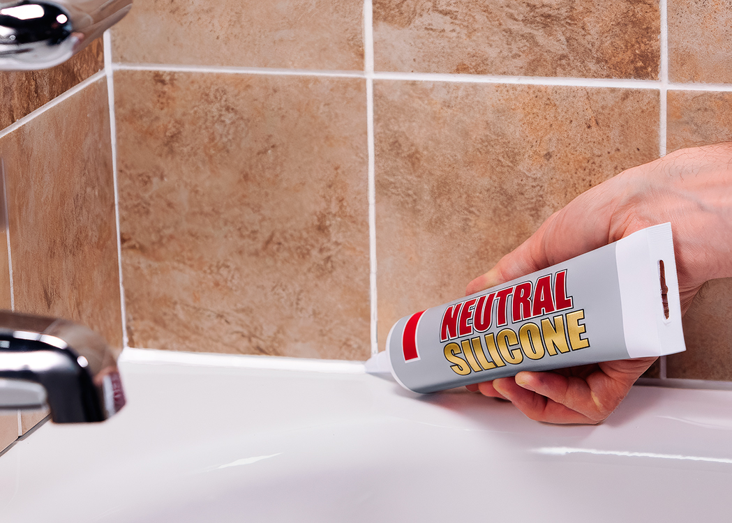 Нанесення нейтрального силіконового герметика на стик між ванною і плиткою у ванній кімнаті