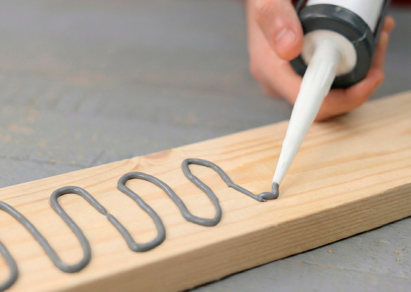 Нанесение серого герметика змейкой на деревянную доску Нанесение серого герметика змейкой на деревянную доску